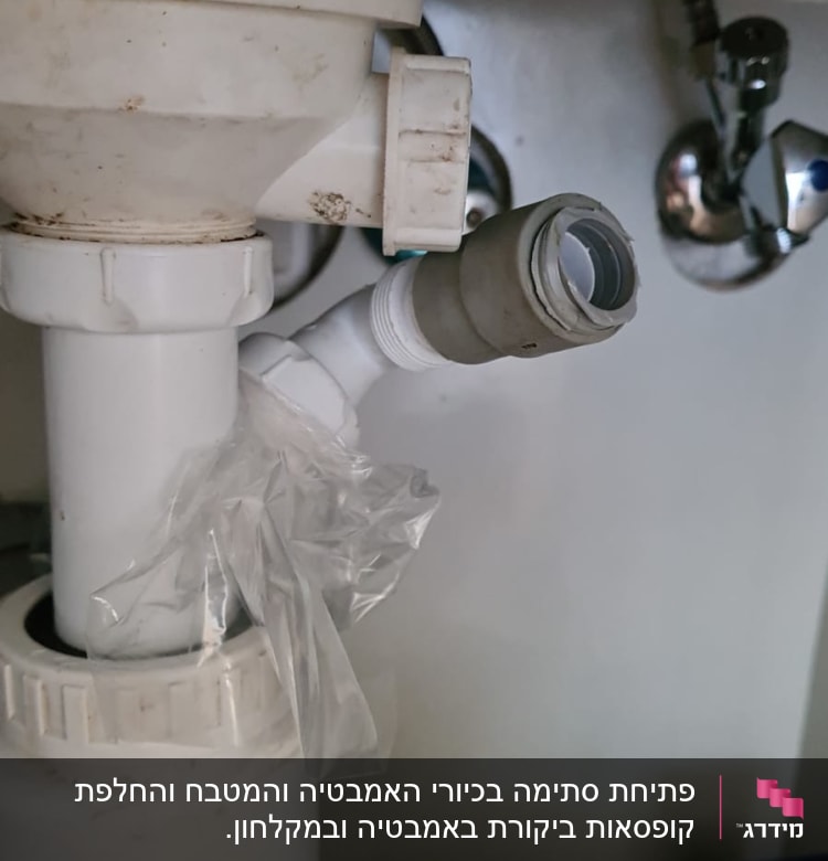 צינור פלסטיק לבן מתחת לכיור עם חיבורי צנרת
